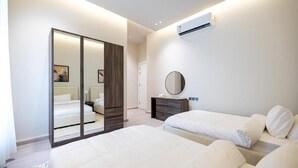 Una camera da letto moderna con due letti, un armadio, uno specchio e un condizionatore d'aria.