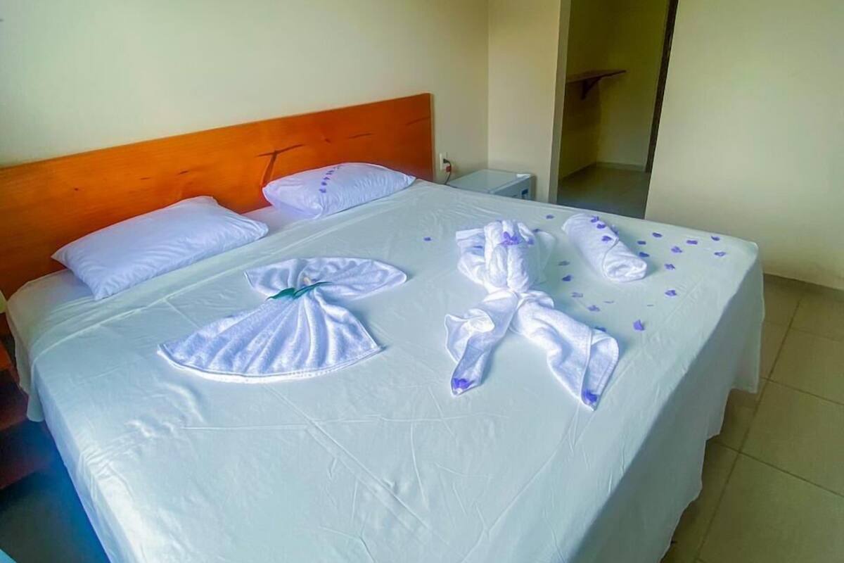 A hotel room with a bed, a nightstand, and a door leading to another room.