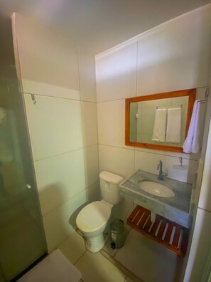 A small bathroom with a toilet, sink, and mirror. - Pousada Vila Miná (Caucaia)