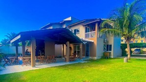 Una casa de dos pisos con un patio cubierto y un césped cuidado.