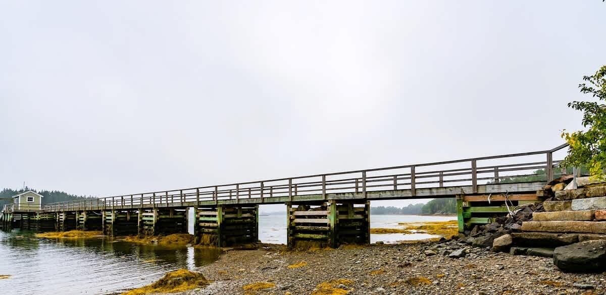 A wooden pier extending into a body of water, with a small building at the end.