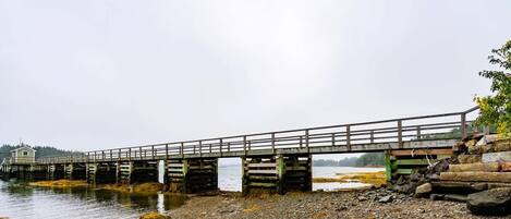 A wooden pier extending into a body of water, with a small building at the end.