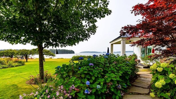 A garden with a stone pathway leading to a gazebo overlooking a lake. - The Cottage at Seaside in Friendship (Friendship)
