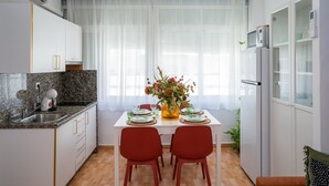 Eine moderne Küche mit weißen Schränken, Granit-Arbeitsplatten und einem Esstisch für zwei Personen mit roten Stühlen.