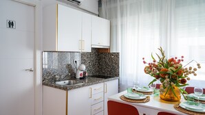 Eine moderne Küche mit Granit Arbeitsplatten, weißen Schränken und einem Essbereich mit Tisch für Zwei.