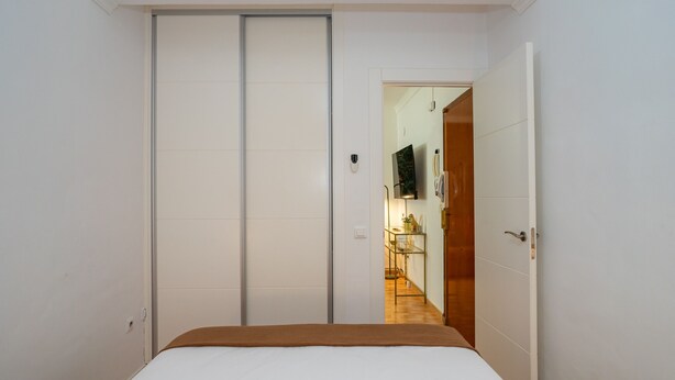 Ein Schlafzimmer mit Bett, Kleiderschrank und einer Tür zum Küchenbereich.