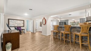 A spacious living area with hardwood flooring, a wooden reception desk, and a dining area with wooden chairs.