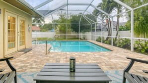 A covered outdoor area with a pool, a table, and chairs.