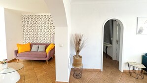 A living room with a sofa, a patterned wall, a vase with dried plants, and a glass coffee table. - Casa Alagoinha by Umbral (Odemira)