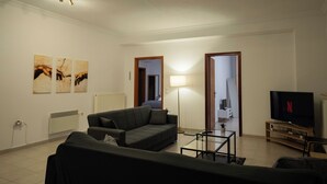 A living room with a sofa, a coffee table, a TV, and artwork on the wall. - Spacious_Home_Kleitoria (Kleitoria)