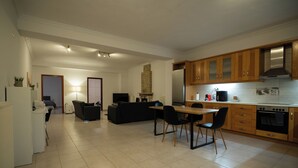 A modern kitchen with wooden cabinets, a built-in oven, and a dining area with a table and chairs. - Spacious_Home_Kleitoria (Kleitoria)