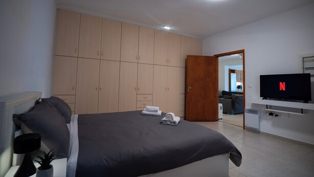 A bedroom with a bed, wardrobe, TV, and a door leading to a living area. - Spacious_Home_Kleitoria (Kleitoria)