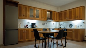 A kitchen with wooden cabinets, a stainless steel refrigerator, a dining table with four chairs, and a coffee maker. - Spacious_Home_Kleitoria (Kleitoria)