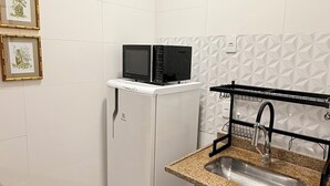 A compact kitchen with a microwave, a sink, and a trash bin. - Loft Copa Charm (Rio de Janeiro)