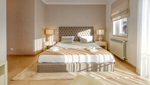 A spacious bedroom with a large bed, two bedside tables, and a window with a view.