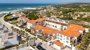 A coastal hotel with multiple buildings, a beach view, and a parking area.