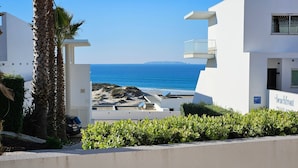 A modern building with a balcony overlooking a beach.