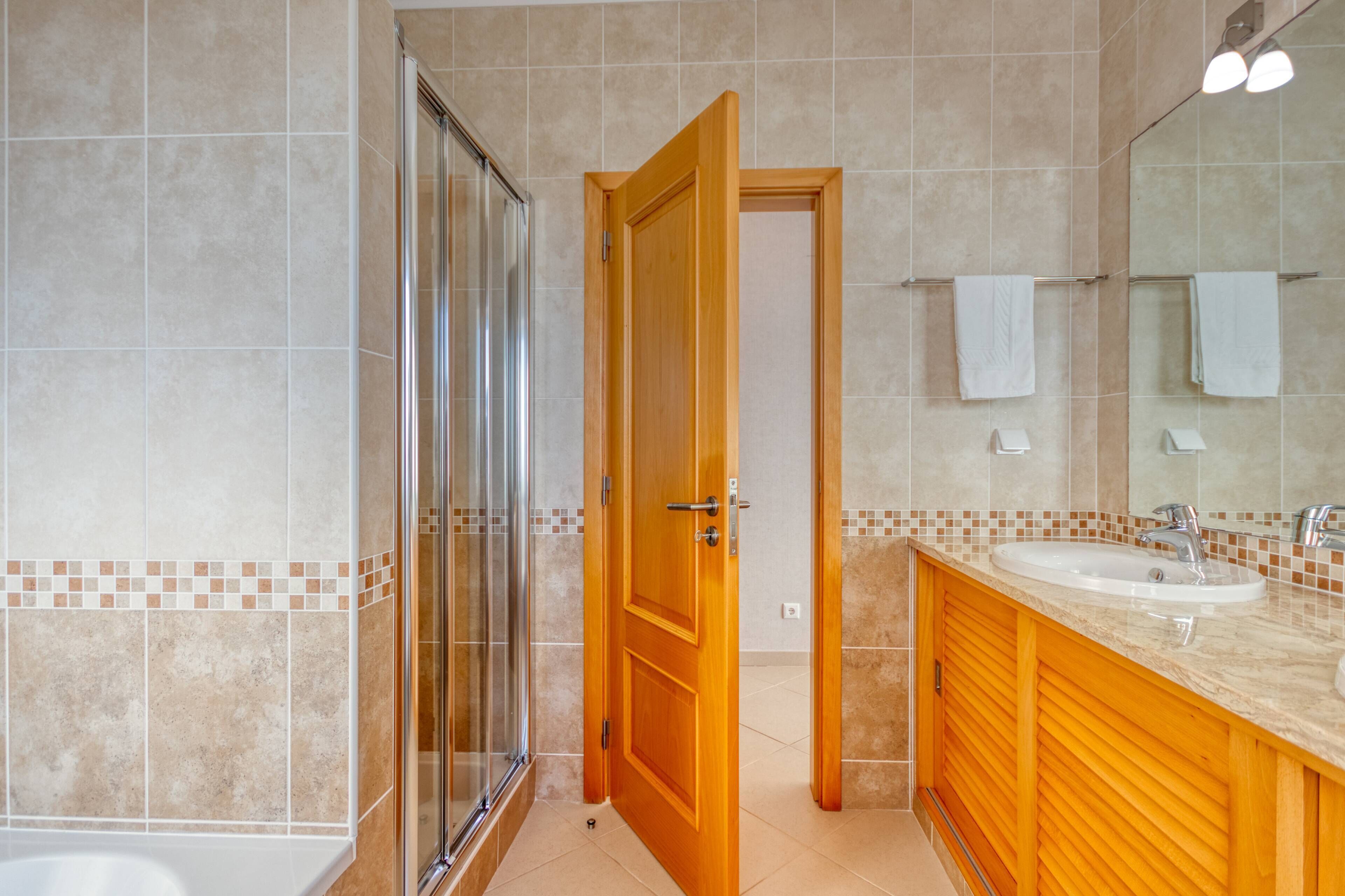 Ein Badezimmer mit Glasdusche, Holzwaschtisch und einem großen Spiegel.