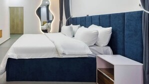 Quarto de hotel moderno com uma cama grande, uma mesa de cabeceira e um ar condicionado instalado.