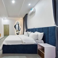 Una habitación de hotel moderna con una cama grande, una mesita de noche y un equipo de aire acondicionado integrado.