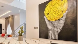 Uma sala de estar moderna com uma mesa de jantar de mármore, um sofá e uma grande pintura de uma mão segurando um globo.