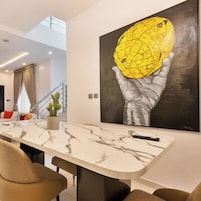 Una sala de estar moderna con una mesa de comedor de mármol, un sofá y un cuadro grande de una mano sosteniendo un globo.