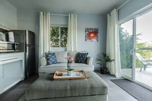 Uma sala de estar moderna com um sofá cinza, uma mesa lateral de madeira e uma planta em vaso.