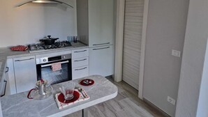 Une cuisine compacte équipée d’une cuisinière à gaz, d’un four et d’un petit coin repas avec une table et des chaises.