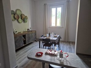 Een eetgedeelte met een tafel voor vier personen, een koffiepot en een decoratief wandobject.