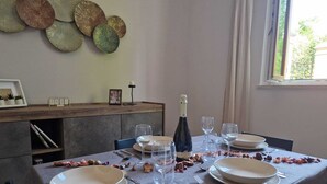 Une table à manger dressée avec des assiettes, des verres et des couverts, une bouteille de vin et des éléments décoratifs sur le mur.