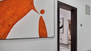 A hallway with a large abstract painting on the wall, a wooden door, and a framed picture on the adjacent wall. - Daveange Hotels (Port Harcourt)