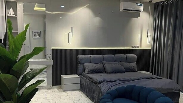 A modern bedroom with a large bed, bedside tables, a wall-mounted air conditioner, and a potted plant. - Daveange Hotels (Port Harcourt)
