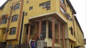 A multi-story yellow building with a prominent entrance and a sign that reads "HARP". - Daveange Hotels (Port Harcourt)