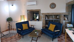 A living room with two blue sofas, a small coffee table, a stone fireplace, and a wall-mounted clock.
