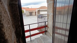 A stone building with a metal gate and a tiled floor leading to a courtyard.