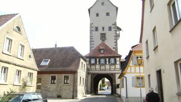 Une rue étroite bordée de bâtiments historiques, une tour de pierre et un arc de triomphe.