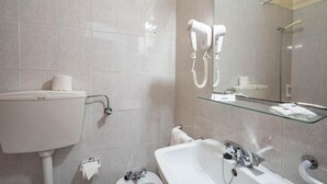 Een badkamer met toilet, wastafel en een glazen plank boven de wastafel.
