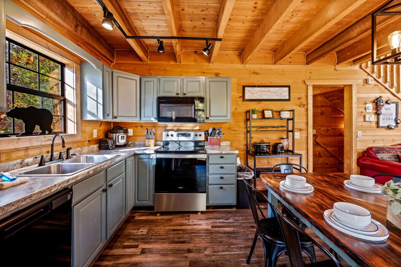 A cozy kitchen with wooden beams, a stove, microwave, and a dining area with a table and chairs.