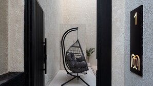 A narrow hallway with a hanging chair, a potted plant, and a wall-mounted sign indicating room number 1. - Nolina chalets (Madinah)
