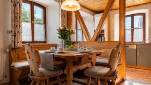 Ein Holzes Esstisch mit vier Stühlen, einer Blumenvase und einer Pendelleuchte.