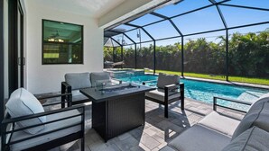 A covered outdoor area with a pool, seating, and a view of the surrounding greenery. - Biohackers Retreat - Heated Pool, Spa, Sauna, Gym (Cape Coral)