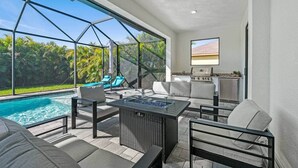 A modern outdoor living area with a pool, seating, and a grill. - Biohackers Retreat - Heated Pool, Spa, Sauna, Gym (Cape Coral)