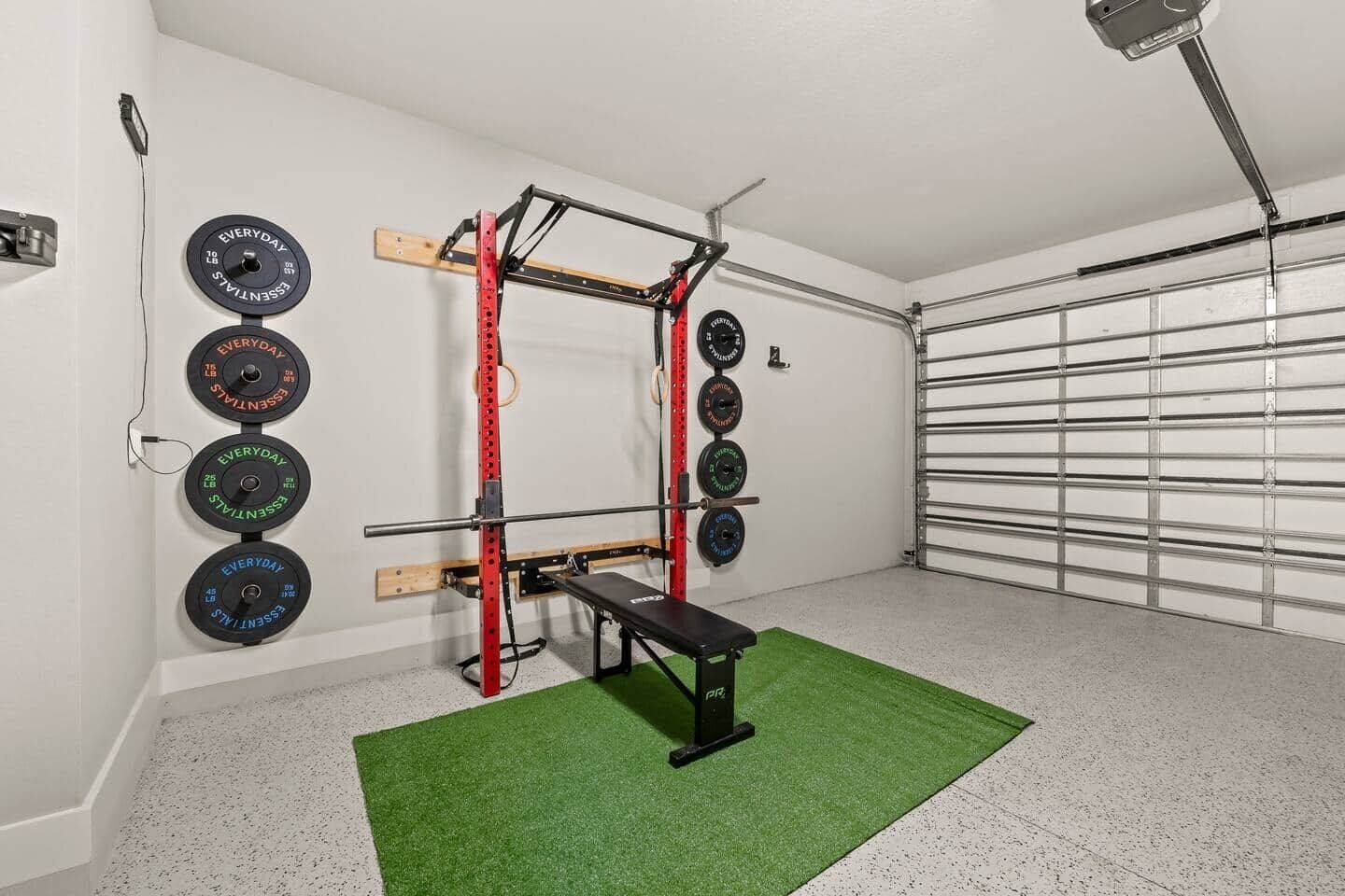 A home gym with a squat rack, bench, and weight plates.