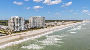 Un hotel costero con varios edificios altos, una playa y cielo despejado.