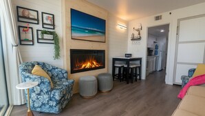 Ein Wohnzimmer mit Kamin, einer Couch, einem Couchtisch und einer Küche im Hintergrund.