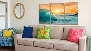 Una sala de estar con un sofá color crema, un sillón azul y una mesita auxiliar verde.