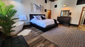 Un dormitorio moderno con una cama grande, una mesita de noche, un espejo y una planta en maceta.
