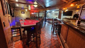 Una sala de casino con una mesa de blackjack, una mesa de billar y una zona de bar.