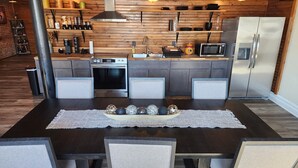 Cocina moderna con isla central, electrodomésticos integrados y comedor con mesa preparada para cuatro.
