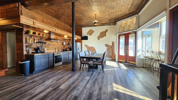 Una cocina amplia con muebles de madera, un comedor con una mesa grande y vistas al exterior a través de ventanas amplias.